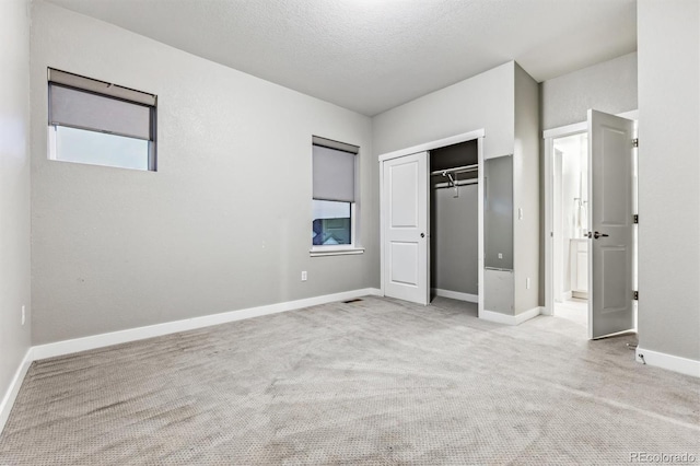 unfurnished bedroom with light colored carpet, a textured ceiling, and a closet