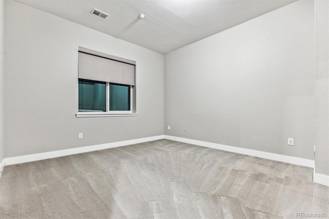 spare room featuring light colored carpet and a textured ceiling