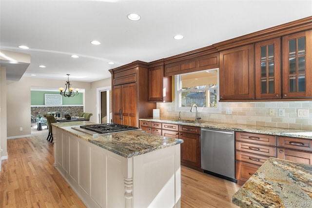 kitchen featuring light stone counters, stainless steel appliances, sink, and hanging light fixtures