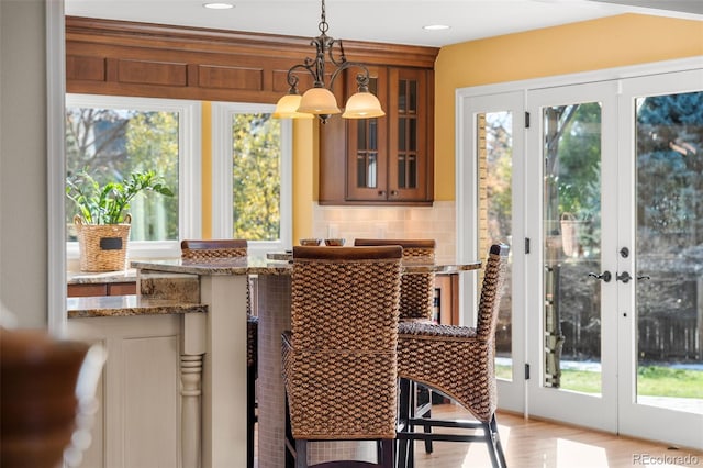 dining area featuring plenty of natural light, light hardwood / wood-style flooring, a notable chandelier, and french doors