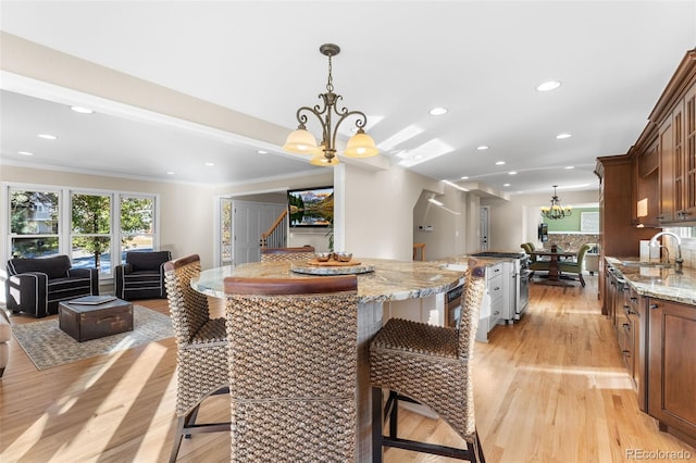 dining space featuring sink, crown molding, light hardwood / wood-style floors, and a chandelier