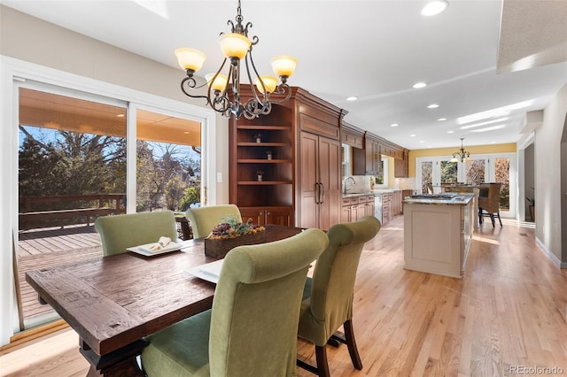 dining area featuring sink, light hardwood / wood-style floors, and a chandelier