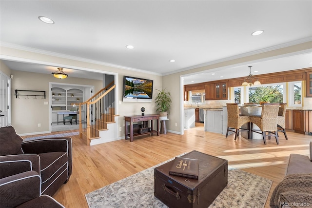 living room with crown molding, a healthy amount of sunlight, light hardwood / wood-style floors, and built in features