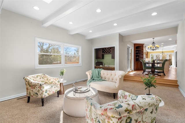 living room with a chandelier, beamed ceiling, and carpet flooring