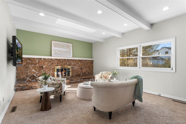 living room with carpet floors, a skylight, a fireplace, and beamed ceiling