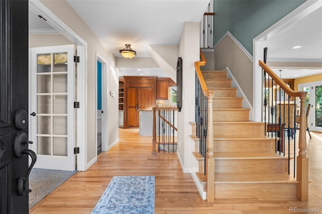 entrance foyer with french doors, ornamental molding, and light hardwood / wood-style floors