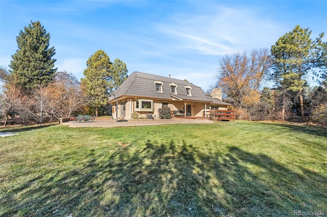 rear view of property featuring a wooden deck, a patio, and a lawn