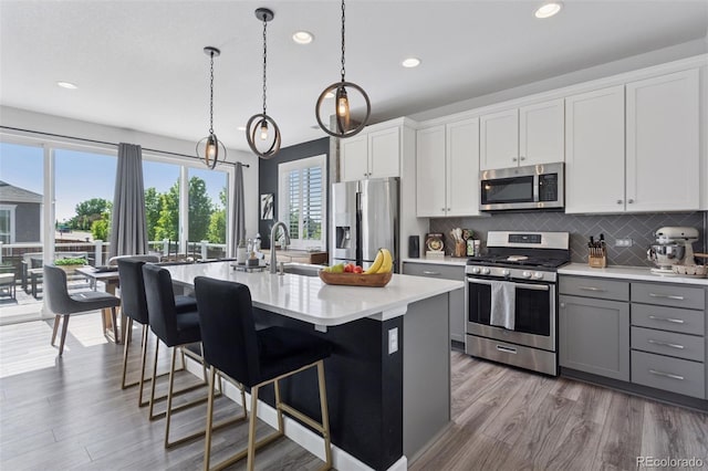 25106 E 1st Ave, Aurora, CO 80018 - kitchen with appliances with stainless steel finishes, recessed lighting, light countertops, decorative backsplash, and a center island with sink