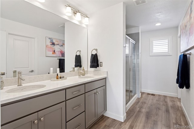 25106 E 1st Ave, Aurora, CO 80018 - bathroom featuring double vanity, a stall shower, and wood finished floors