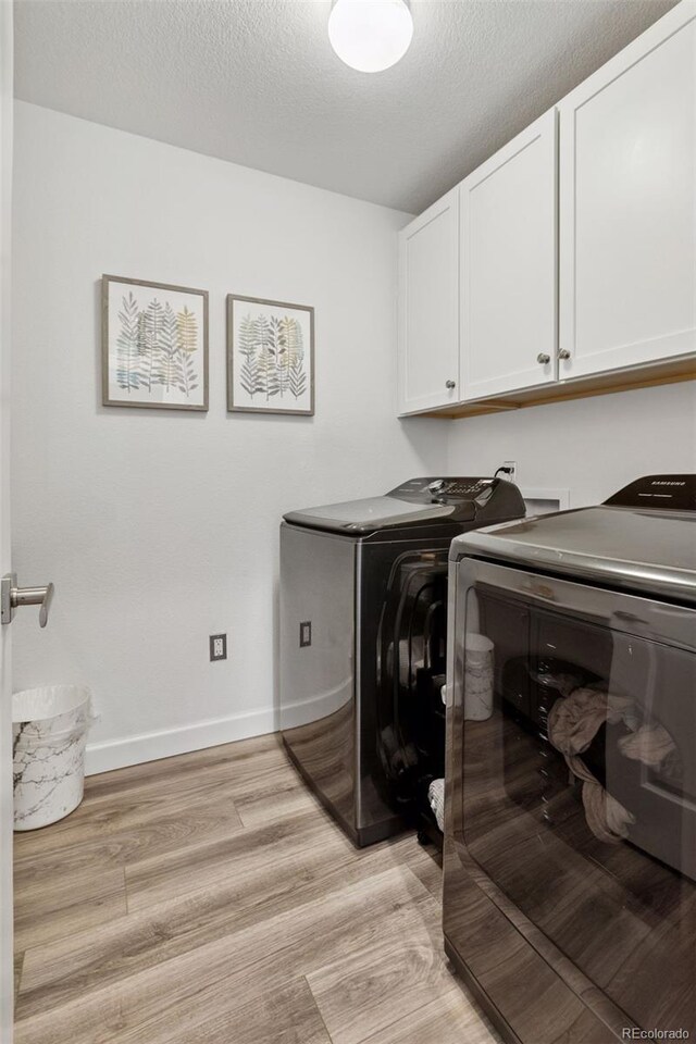 25106 E 1st Ave, Aurora, CO 80018 - washroom featuring cabinet space, separate washer and dryer, light wood-style floors, and a textured ceiling