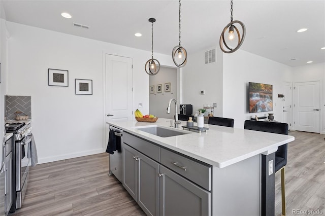 25106 E 1st Ave, Aurora, CO 80018 - kitchen featuring stainless steel appliances, gray cabinets, light wood-style flooring, recessed lighting, and a kitchen island with sink