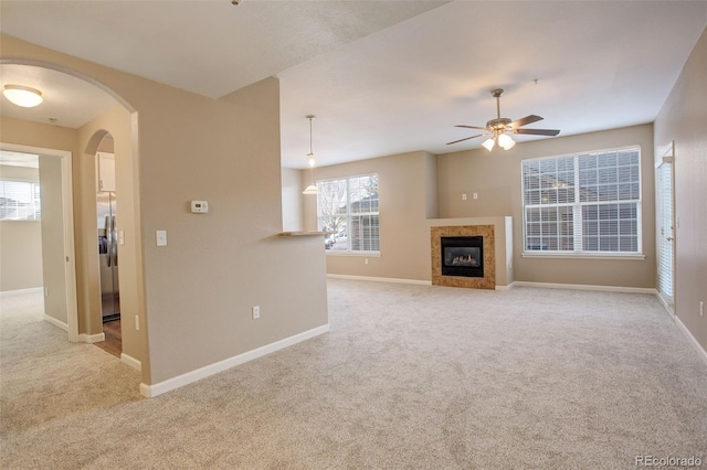 unfurnished living room featuring ceiling fan, light carpet, and a tiled fireplace