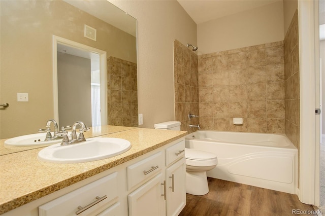 full bathroom with vanity, toilet, wood-type flooring, and tiled shower / bath