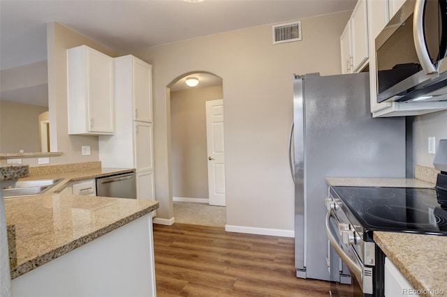 kitchen featuring light stone countertops, appliances with stainless steel finishes, sink, wood-type flooring, and white cabinets