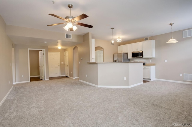 kitchen with ceiling fan, light colored carpet, decorative light fixtures, white cabinets, and appliances with stainless steel finishes