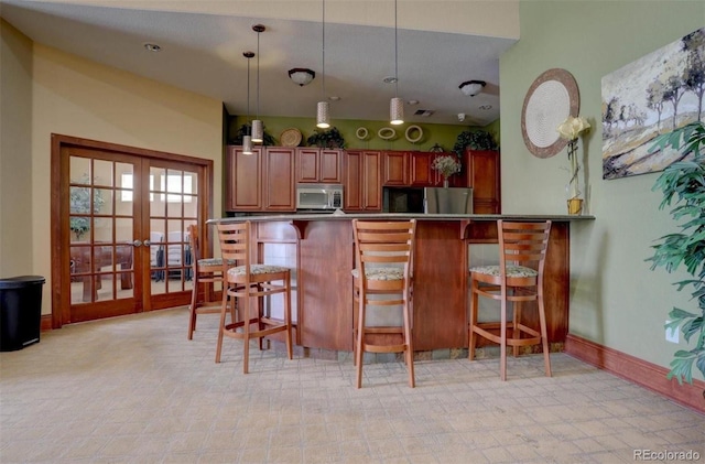 kitchen with a breakfast bar, kitchen peninsula, hanging light fixtures, and appliances with stainless steel finishes