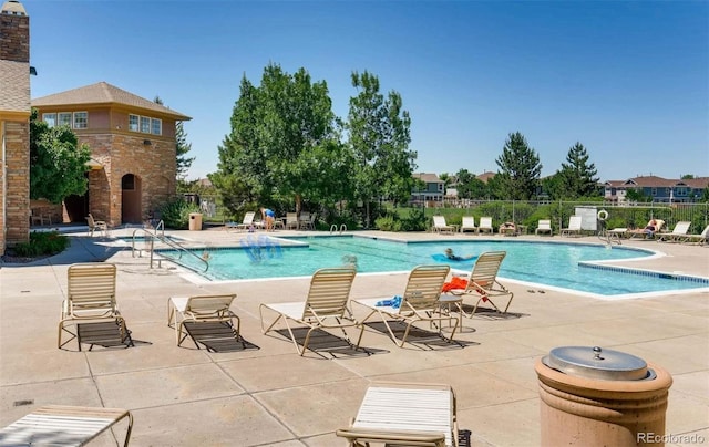 view of swimming pool featuring a patio and an outdoor stone fireplace