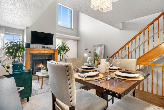 5155 W 68th Ave Unit 5, Westminster, CO 80030 - dining room featuring a textured ceiling, a warm lit fireplace, stairs, a chandelier, and high vaulted ceiling