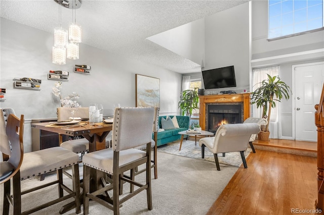5155 W 68th Ave Unit 5, Westminster, CO 80030 - dining space featuring a textured ceiling, a lit fireplace, light wood-type flooring, and a high ceiling