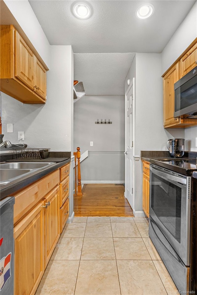 5155 W 68th Ave Unit 5, Westminster, CO 80030 - kitchen featuring appliances with stainless steel finishes, dark countertops, light tile patterned floors, a sink, and baseboards