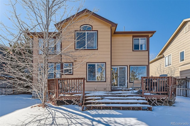 snow covered rear of property with a deck