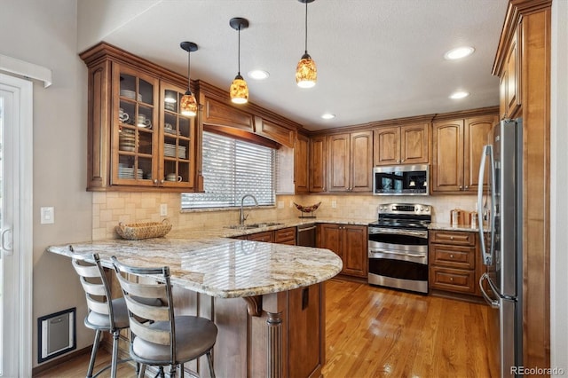 7354 S Robb St, Littleton, CO 80127 - kitchen featuring appliances with stainless steel finishes, a sink, a peninsula, brown cabinetry, and recessed lighting
