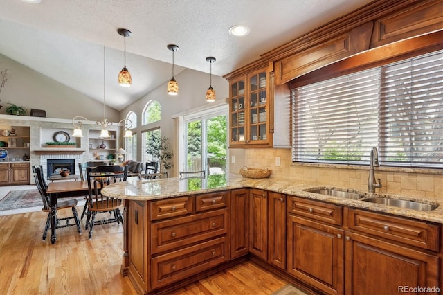 7354 S Robb St, Littleton, CO 80127 - kitchen with a sink, vaulted ceiling, light wood-style flooring, decorative backsplash, and glass insert cabinets