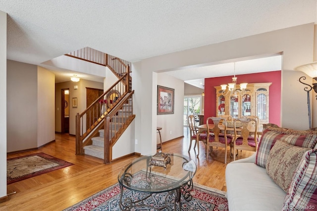 7354 S Robb St, Littleton, CO 80127 - living room with wood finished floors, stairway, a chandelier, a textured ceiling, and baseboards