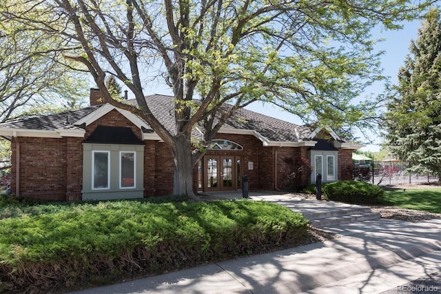 7354 S Robb St, Littleton, CO 80127 - view of front of home with french doors, brick siding, a chimney, and fence