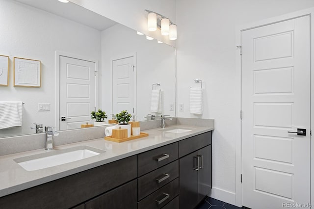 bathroom featuring double vanity, a sink, tile patterned floors, and baseboards