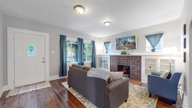 living room with a tile fireplace and dark hardwood / wood-style flooring