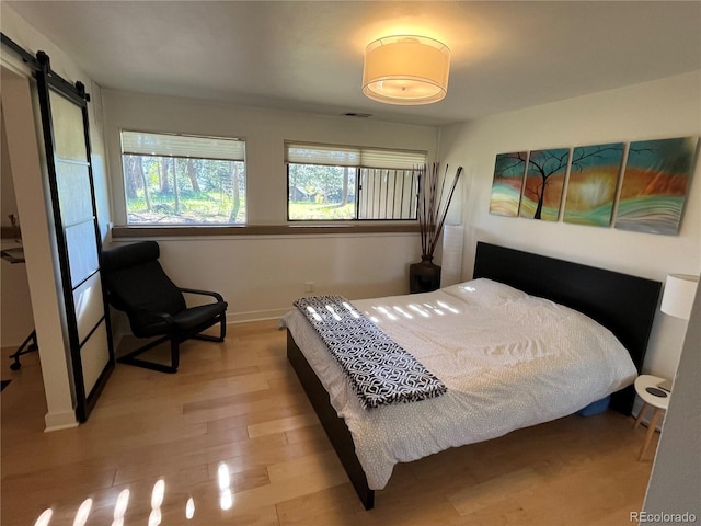 24226 Currant Dr, Golden, CO 80401 - bedroom with baseboards, a barn door, and wood finished floors