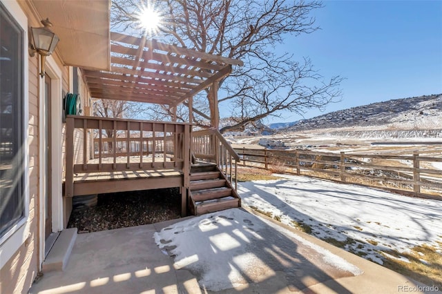 snow covered deck featuring a mountain view, a pergola, and a patio area