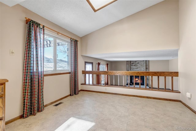 empty room featuring a brick fireplace, a textured ceiling, and lofted ceiling