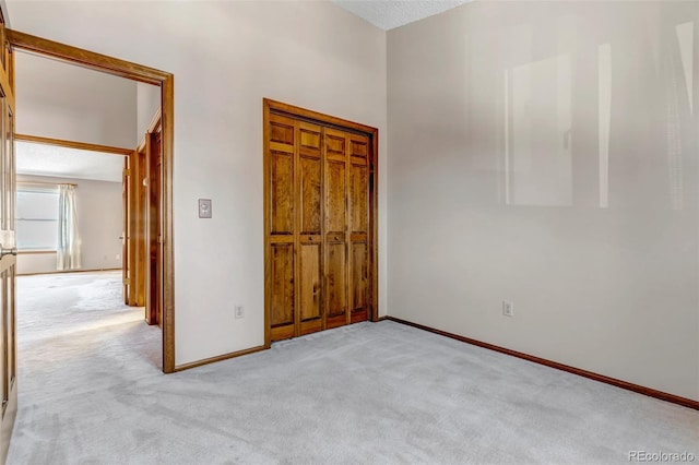 unfurnished bedroom featuring a closet, light colored carpet, and a textured ceiling