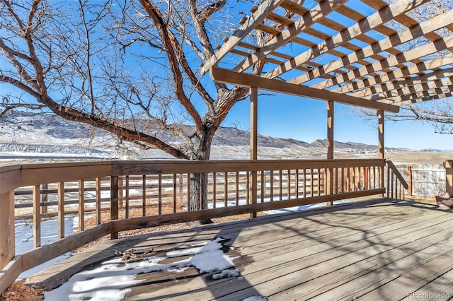 snow covered deck with a mountain view and a pergola