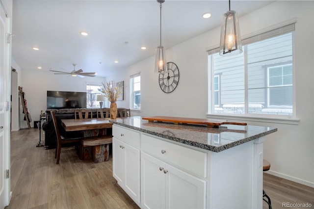 23670 E 41 St Ave, Aurora, CO 80019 - kitchen with light wood-style flooring, stone countertops, white cabinetry, a kitchen island, and a ceiling fan
