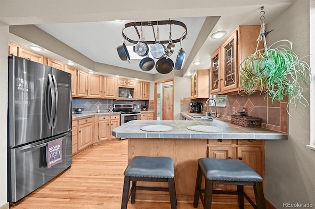 13540 Deer Ridge Way, Larkspur, CO 80118 - kitchen with stainless steel appliances, light brown cabinets, a peninsula, glass insert cabinets, and backsplash