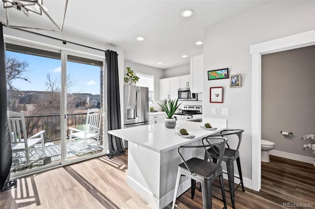 kitchen with white cabinets, stainless steel appliances, dark wood-type flooring, and kitchen peninsula