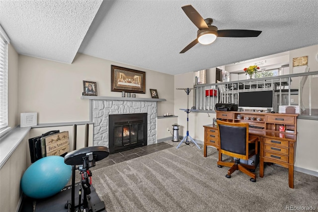 11323 Albion St, Thornton, CO 80233 - home office with a textured ceiling, ceiling fan, a stone fireplace, and carpet flooring