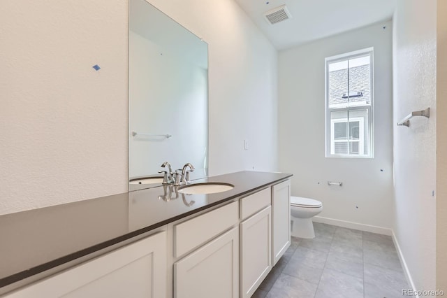 bathroom featuring toilet, vanity, baseboards, and tile patterned flooring