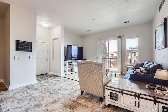 living area with a textured ceiling, visible vents, and baseboards