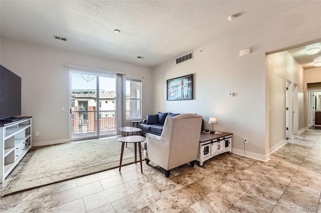 living room featuring visible vents, a textured ceiling, and baseboards