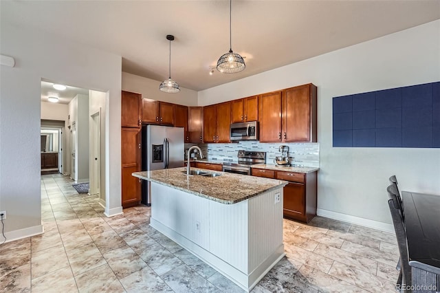 kitchen featuring light stone counters, brown cabinets, decorative backsplash, appliances with stainless steel finishes, and a sink