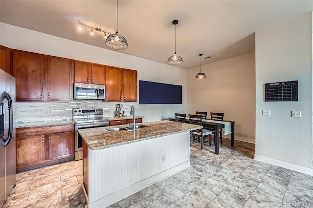 kitchen featuring decorative backsplash, appliances with stainless steel finishes, brown cabinets, light stone countertops, and a sink