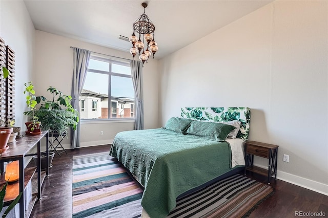 bedroom featuring an inviting chandelier, wood finished floors, visible vents, and baseboards