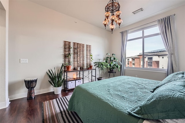 bedroom with a notable chandelier, baseboards, visible vents, and wood finished floors