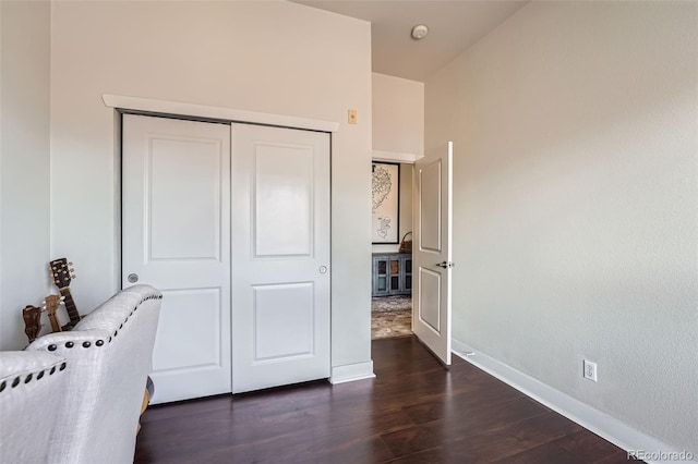 bedroom featuring dark wood-style floors, baseboards, and a closet