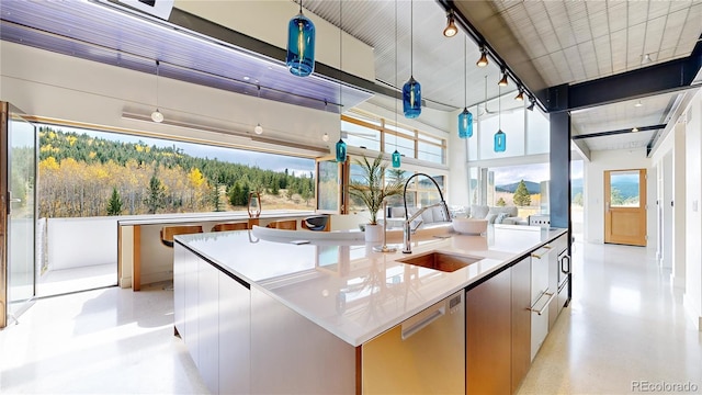 kitchen featuring dishwasher, sink, an island with sink, hanging light fixtures, and white cabinetry