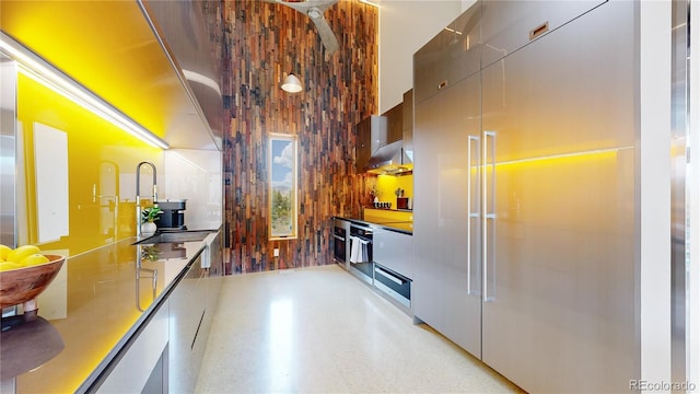 kitchen featuring oven, a high ceiling, extractor fan, and wood walls